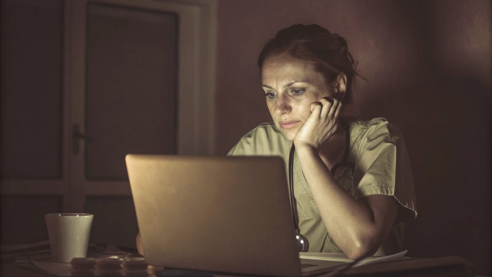 A lonely medical student staring at a blank computer screen in a dark, blue-lit room